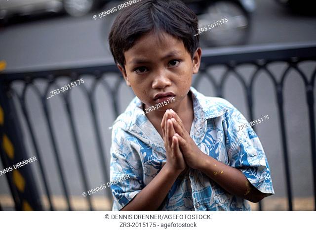 A young boy begs to tourists in Phnom Penh, Cambodia