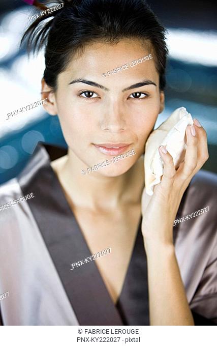Portrait of a woman touching a conch shell on her face