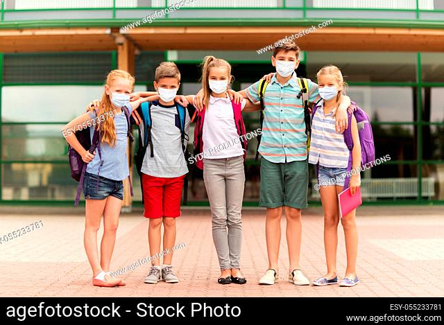 group of students in masks hugging over school