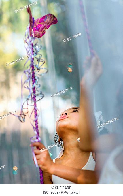 Young girl dressed as fairy, holding wand, playing outdoors