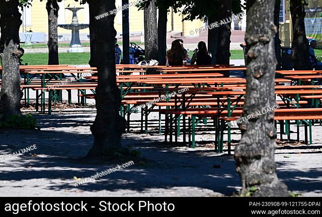 08 September 2023, Baden-Württemberg, Karlsruhe: Only a few passers-by are sitting on benches in the sun in the park in front of the castle in Karlsruhe in...
