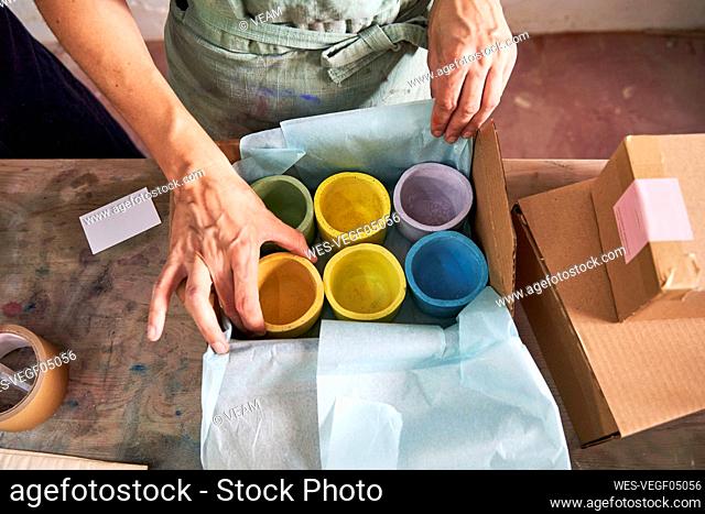 Female store owner arranging colorful design concretes in box at workshop