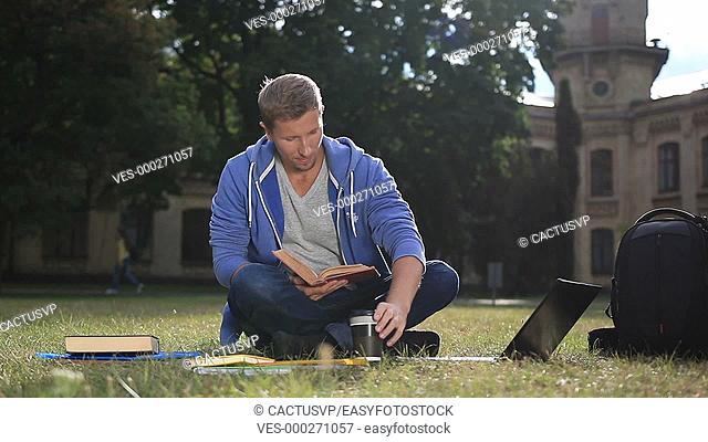 Happy young student reading a book in the park