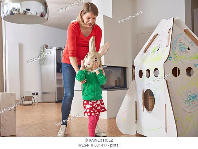 Mother and daughternwith bunny mask at cardboard rocket