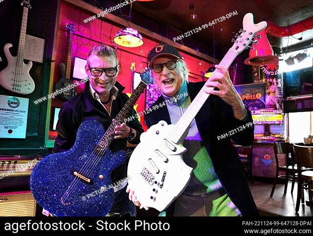 24 November 2022, Hamburg: Guitar maker Jens Ritter (l) holds up the ""25th Anniversary of Magic & Freedom"" guitar, studded with more than 11