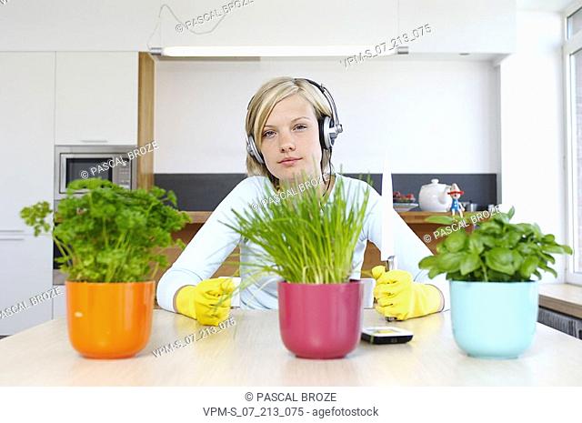 Portrait of a young woman holding a knife and sitting in front of a potted plants