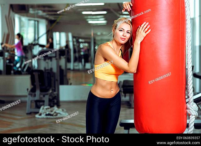 Tired young woman training with punching bag after training at the gym