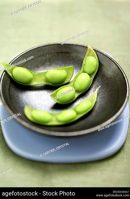 Three half soya bean pods in black bowl