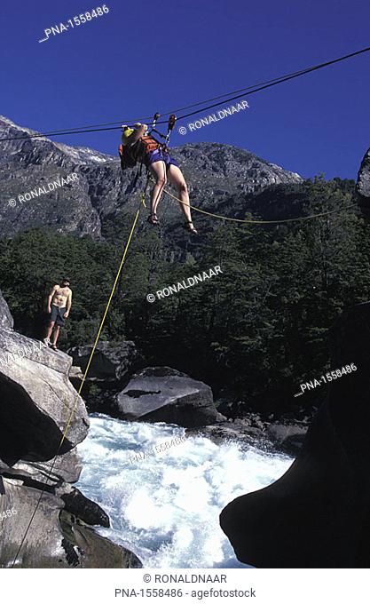 Man suspended in a Tyrolienne above the river Futaleuvu, Patagonia, Chile