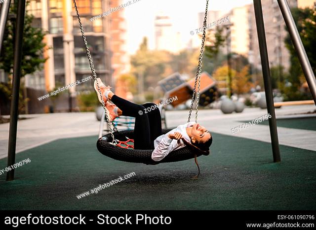 Young woman rides on a swing. Girl resting on the playground