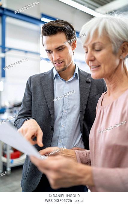 Businessman and senior woman looking at plan in a factory