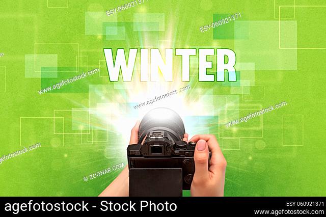 Close-up of a hand holding digital camera with WINTER inscription, traveling concept