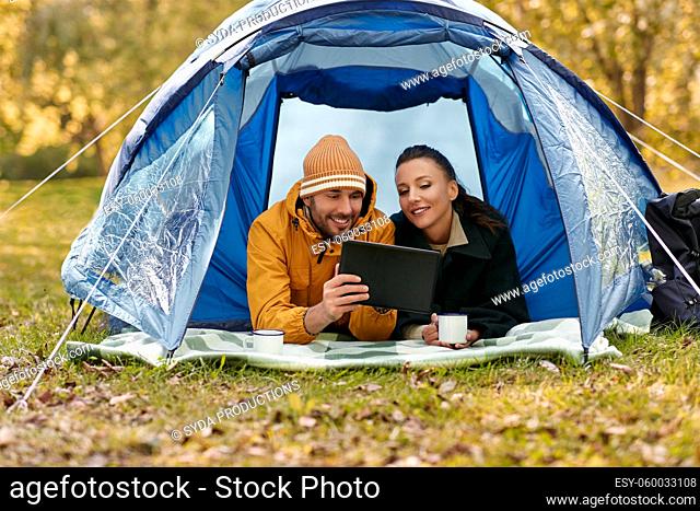 couple with tablet pc drinking tea inside tent