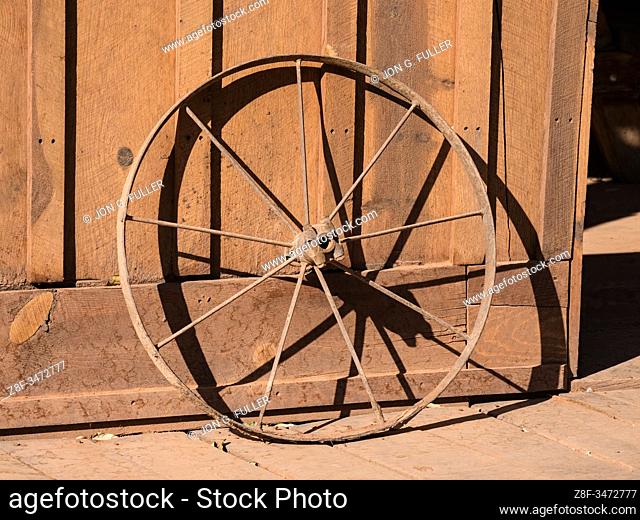 An old rusty metal rim from a wagon wheel leans against the wall of the tack barn on a ranch near Moab, Utah