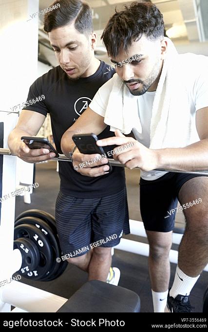 Two men looking at smart phones in gym