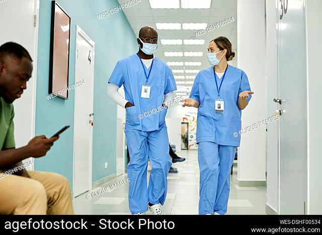 Medical colleagues discussing with each other walking in hospital corridor