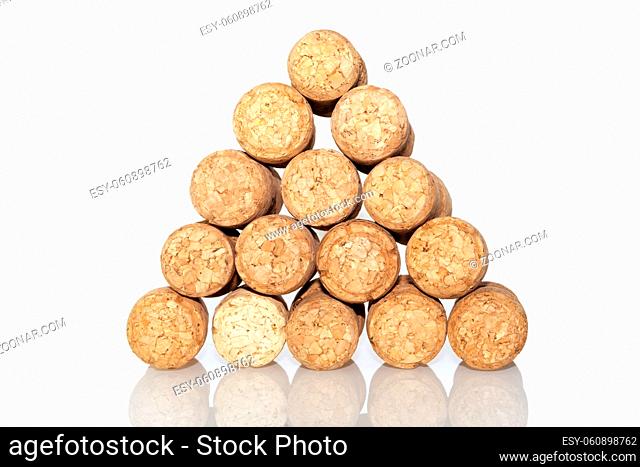 small pyramid made from blank champagne corks isolated on white reflective surface