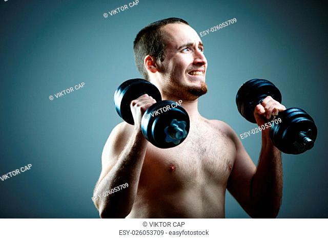 Close up of young man lifting weights over grey background