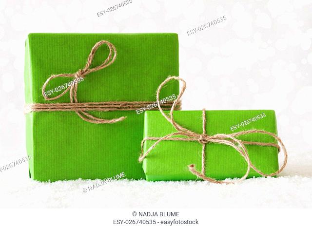 Two Green Christmas Gift Or Present On Snow. Card For Birthday Or Seasons Greetings. Natural looking Ribbon. Background With White Bokeh Effect