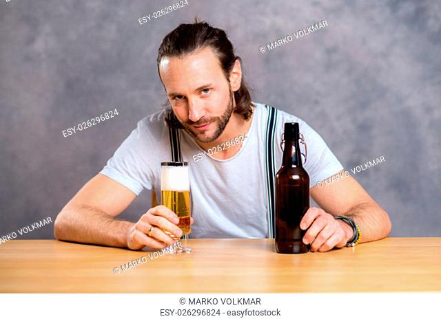 young man in front of gray background drinking beer
