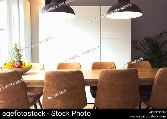 Modern wooden table with set of stylish chairs, houseplant, fruit in retro dining room, new interior design house close up