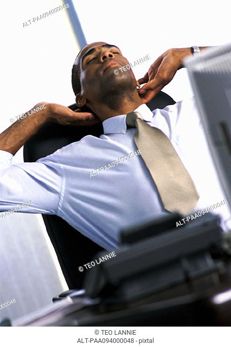 Businessman stretching in armchair