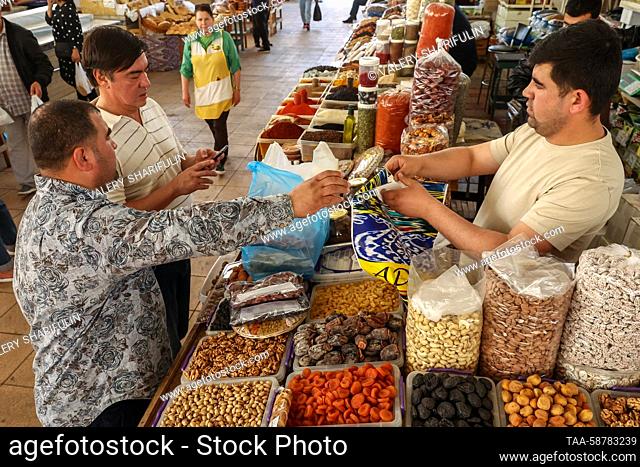 UZBEKISTAN, TASHKENT - MAY 1, 2023: Customers at a stall selling dried fruit and nuts at Oloy Bazaar. Valery Sharifulin/TASS