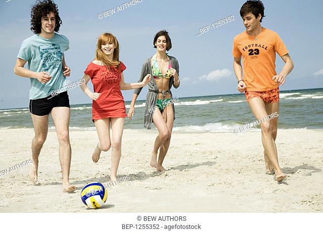 Four friends playing volleyball on the beach
