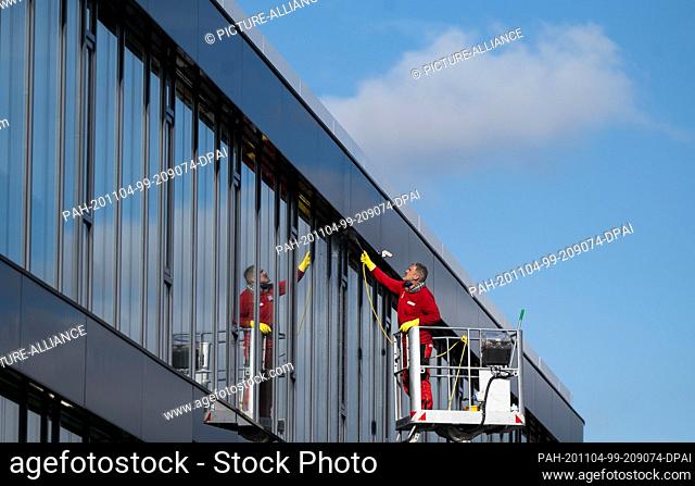 04 November 2020, Baden-Wuerttemberg, Karlsruhe: A man cleans the windows of a building. Photo: Marijan Murat/dpa. - Karlsruhe/Baden-Wuerttemberg/Germany
