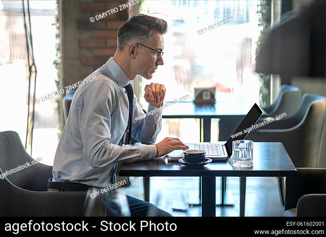 Working remotely. A businessman working on a laptop in a cafe