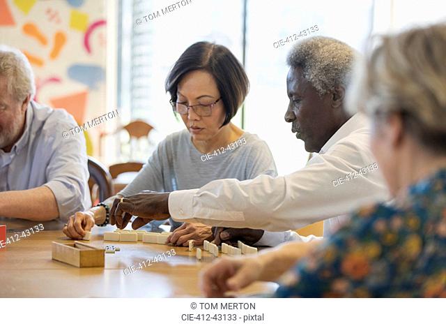 Senior friends playing mahjong at table in community center