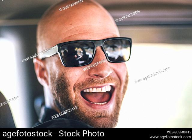 Portrait of happy young man with sunglasses and beard on a road trip