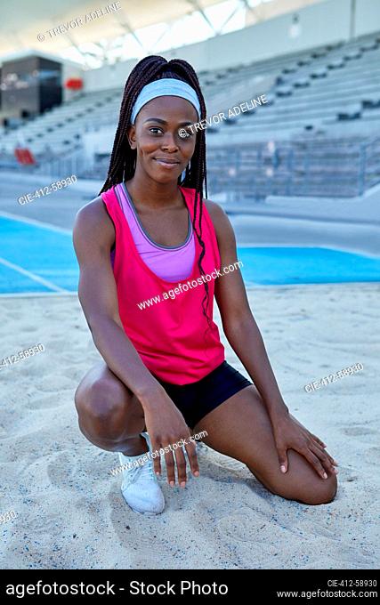 Portrait confident female track and field athlete in long jump sand