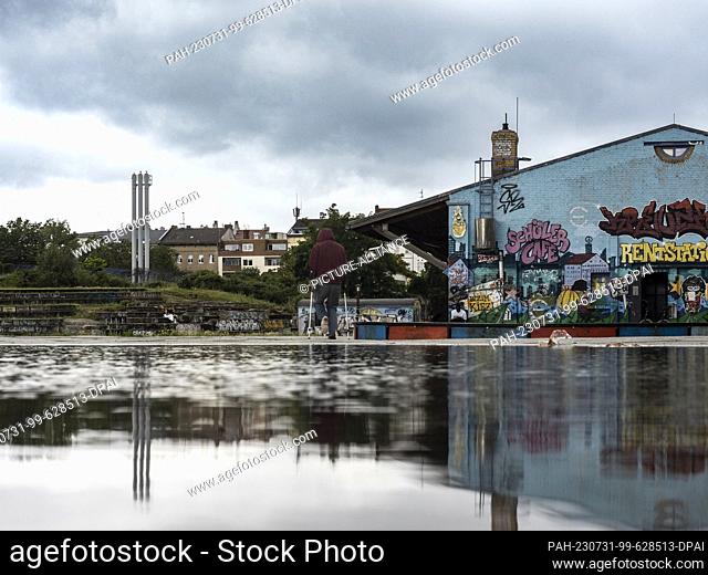 31 July 2023, Berlin: Clouds are reflected in a puddle of rain in Görlitzer Park. The green space in Kreuzberg is always a source of discussion
