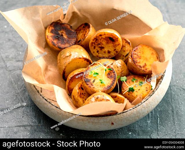 Roasted baby potatoes and microgreen in craft plate on gray background. Baby potato half, roasted