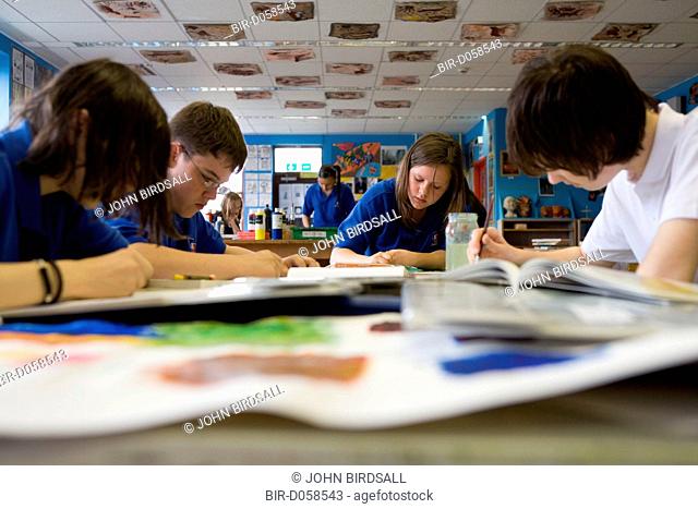 Group of students painting and drawing working towards a final piece in the Art class