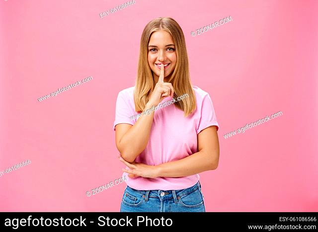Shh keep it secret. Portrait of charismatic cheerful chubby girl with tanned skin and fair hair showing shush gesture with index finger over mouth smiling...