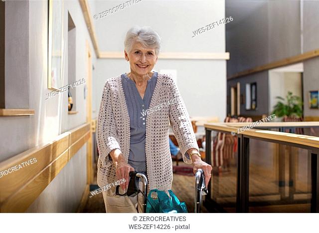 Senior woman in retirement home pushing wheeled walker