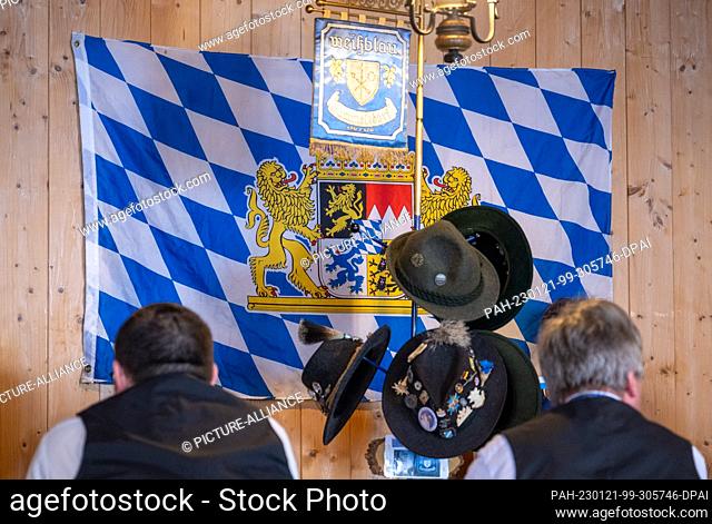 21 January 2023, Bavaria, Gammelsdorf: At the regulars' table of the Königstreuen weiß-blau Gammelsdorf two Trachtler sit in front of the Bavarian flag