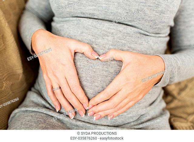 pregnant woman making heart gesture on her belly