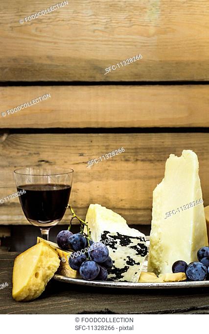 A cheese platter with grapes and a glass of red wine