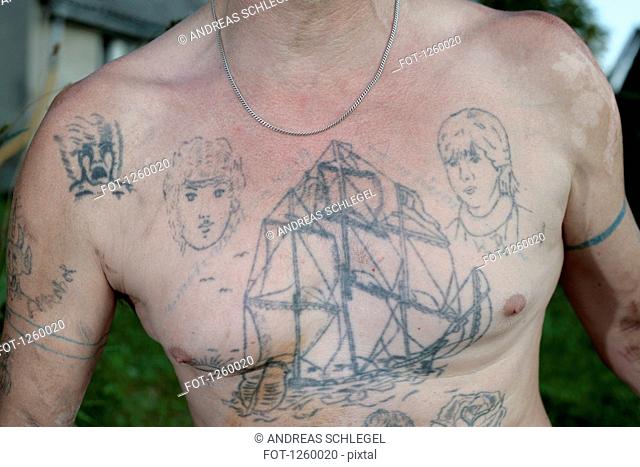 A mature man's chest with faded tattoos