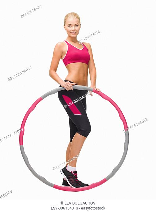fitness, sport and healthcare concept - young sporty woman with hula hoop