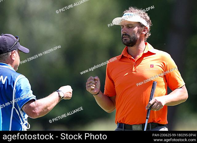 25 June 2023, Bavaria, Munich: Golf: Europe Tour - International Open, Singles, Men, 4th round, Joost Luiten (NED) on the green tees off the caddy Photo:...