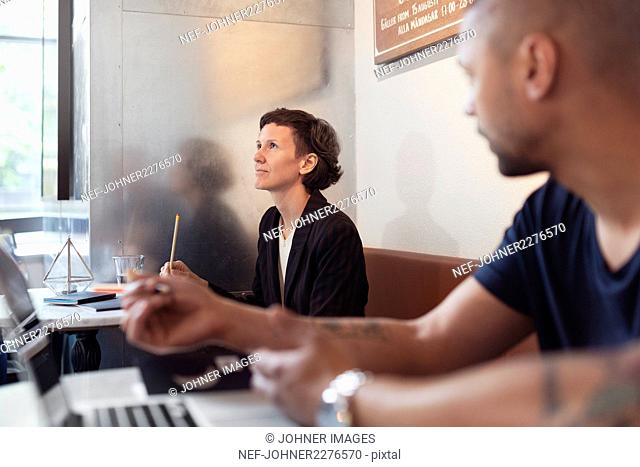 Woman sitting in restaurant and man in foreground