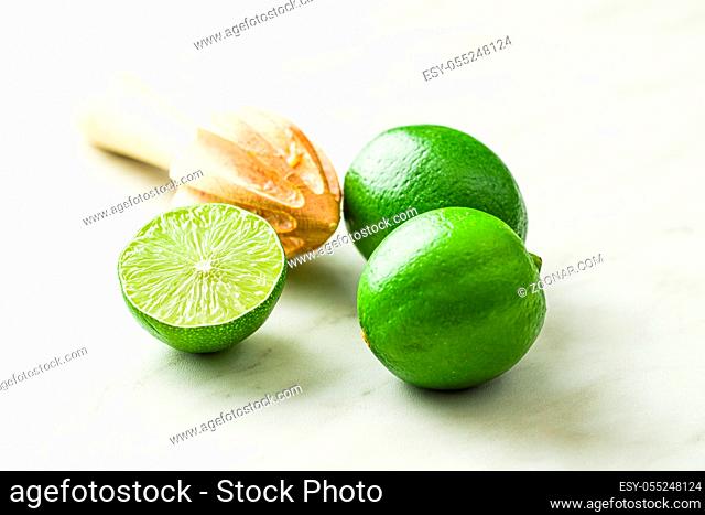 Wooden citrus squeezer and green lime on kitchen table