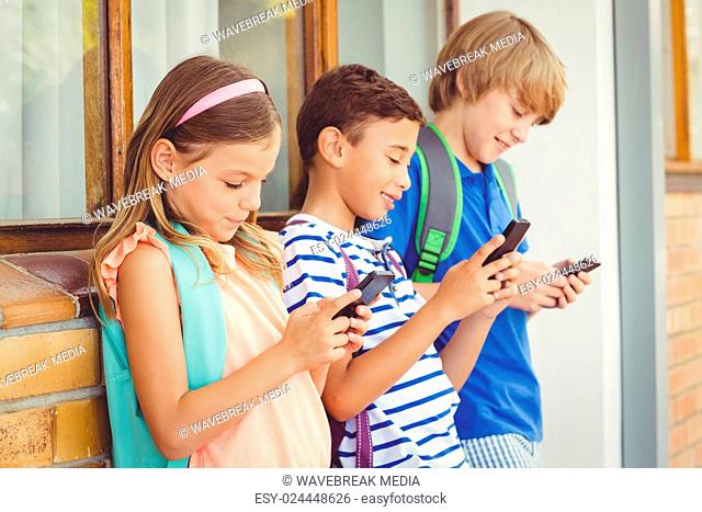 School kids using mobile phone in corridor