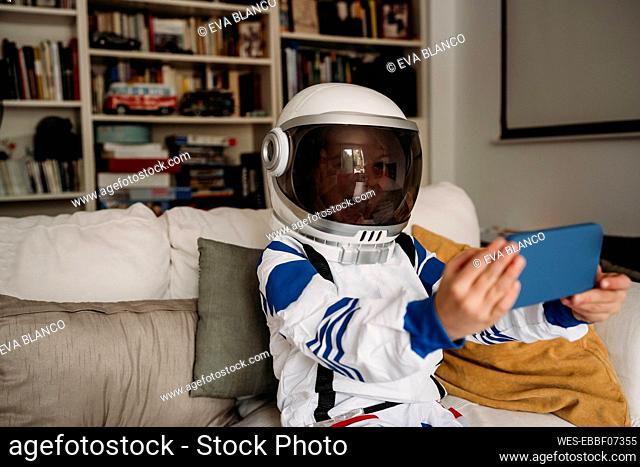 Girl wearing space costume having video call on mobile phone at home