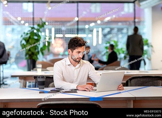 Businessman working over laptop at desk in office