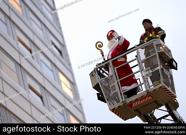 06 December 2023, Lower Saxony, Göttingen: A costumed Santa Claus is driven along the south façade of Göttingen Children's Hospital on a fire ladder